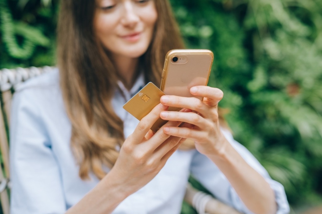 Woman holding phone and card.